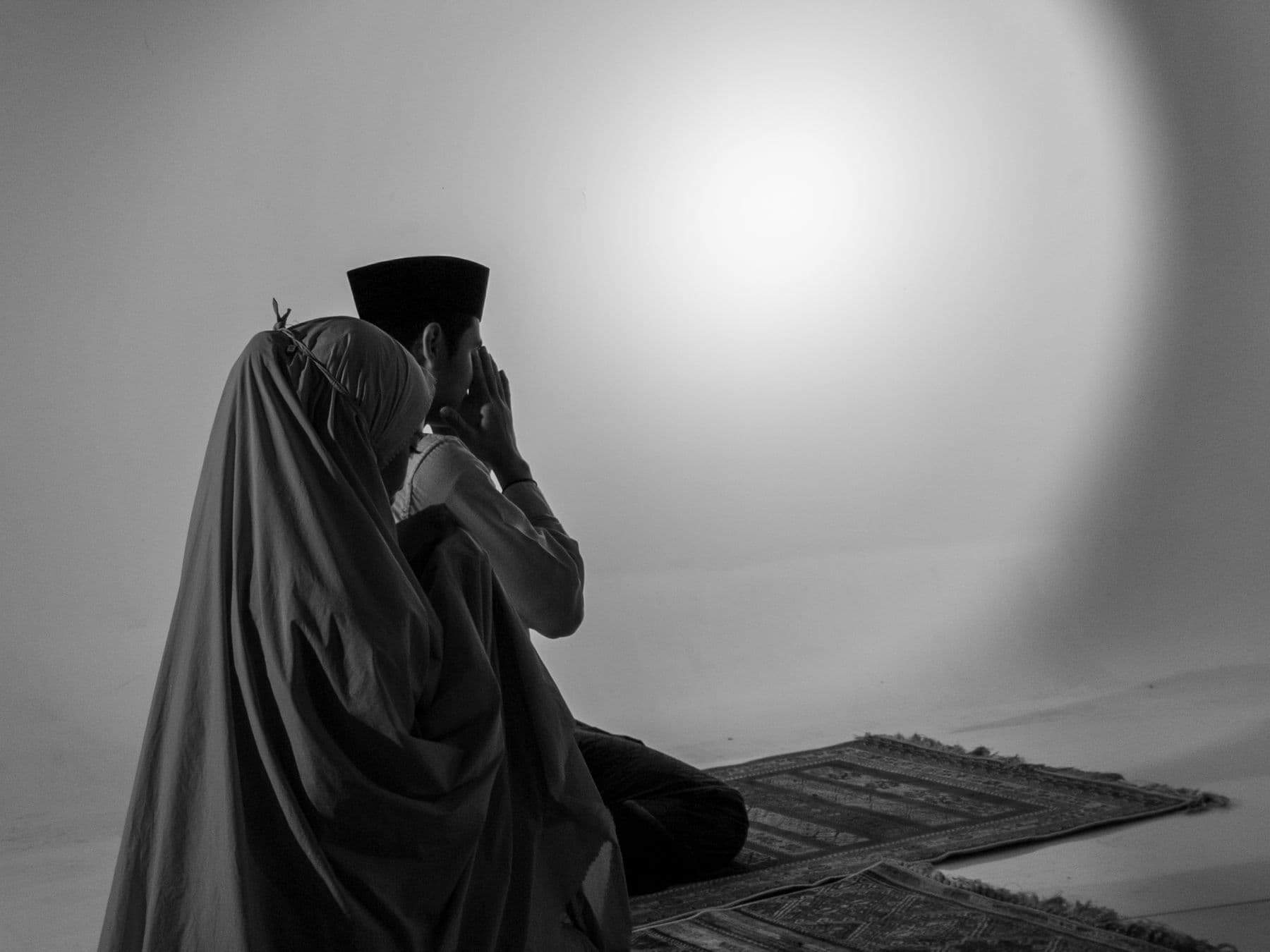 A Muslim couple praying side by side on prayer mats