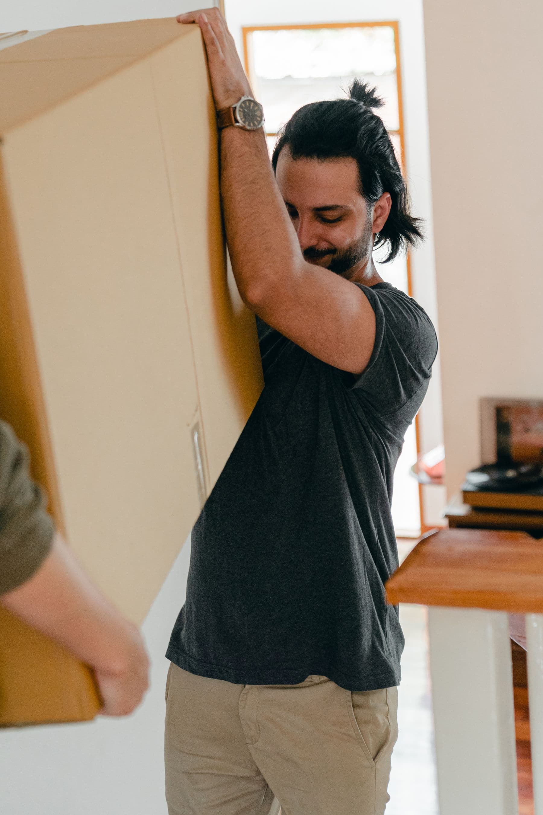 Two people carrying a moving box together in a bright home